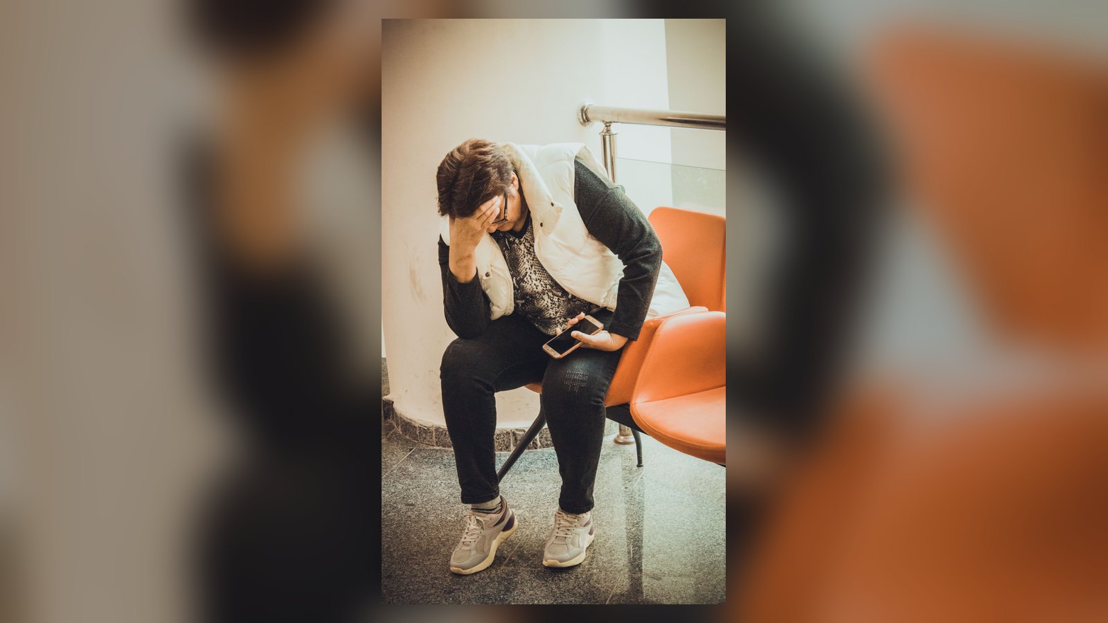 Pessoa preocupada em uma sala de espera, com a mão sobre o rosto