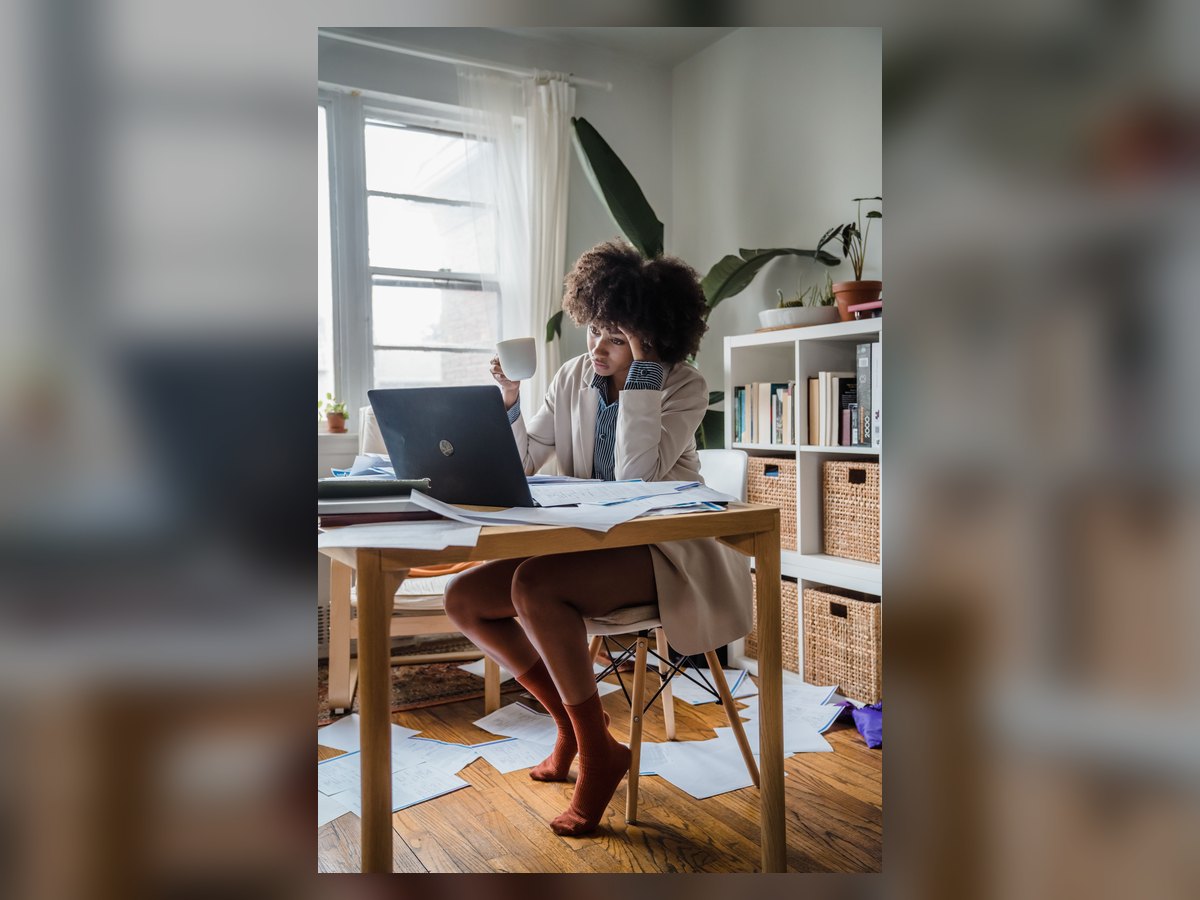 Profissional cansada diante de um computador e documentos de trabalho