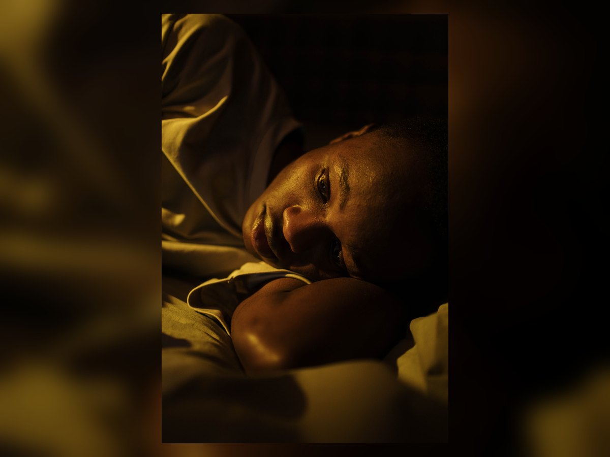 Pessoa acordada na cama durante a noite, representando dificuldade para dormir