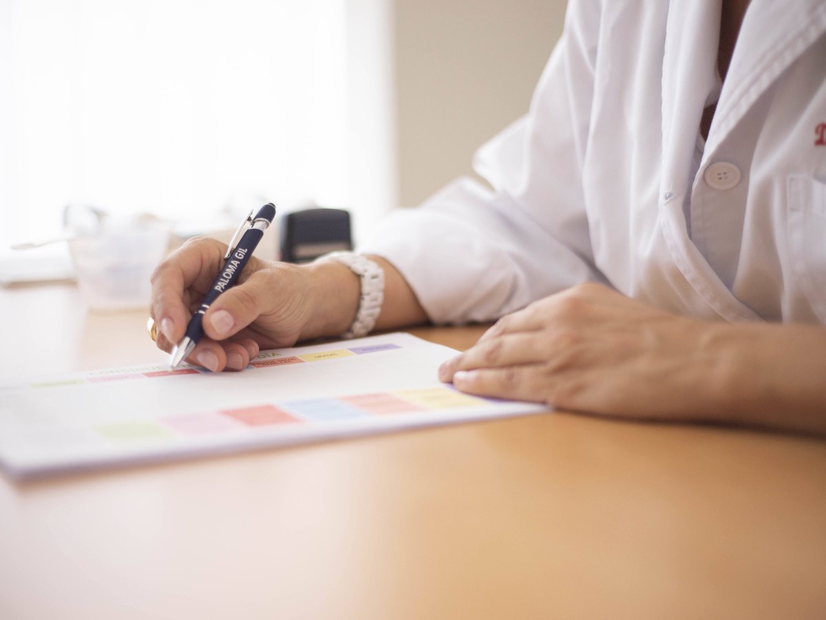 Médica escrevendo uma prescrição em uma mesa de atendimento
